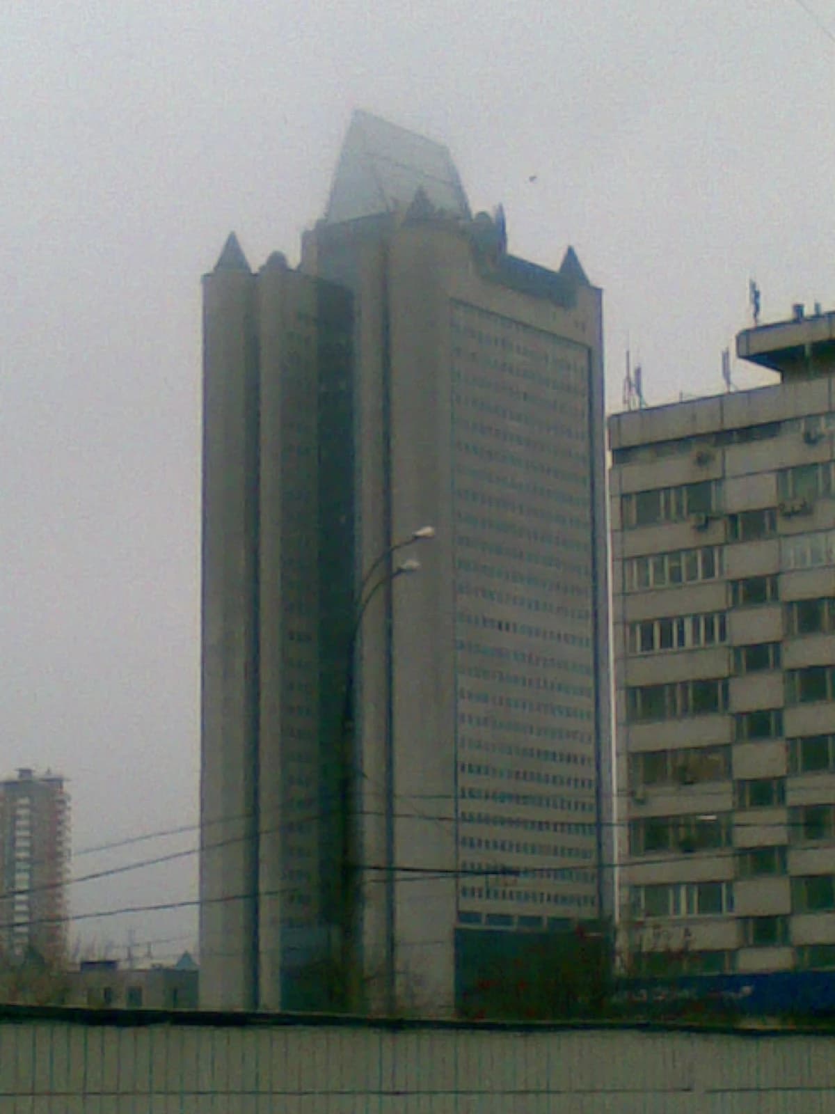 Gazprom Headquarters building, a tall grey skyscraper, stands under a cloudy sky.