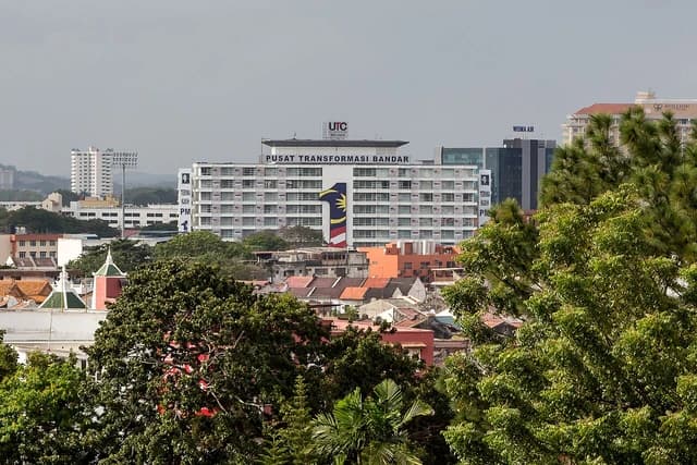 An aerial view of the UTC Melaka building and surrounding cityscape in Malaysia.