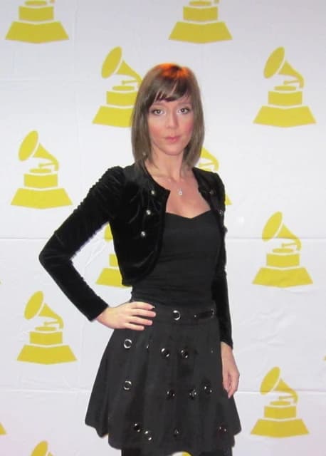 Lili Roquelin poses in front of a backdrop with Grammy logos.