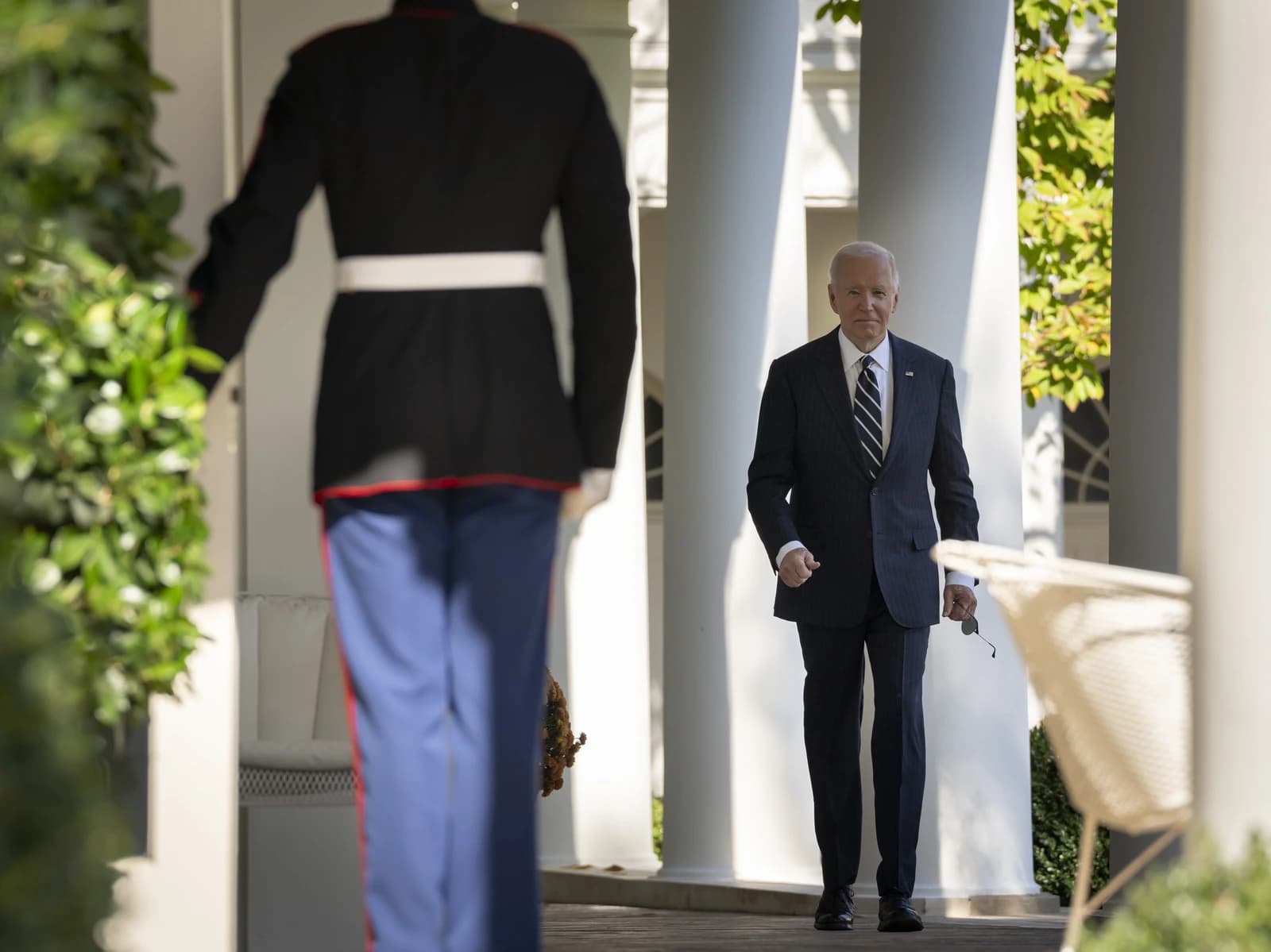 President Joe Biden walks on a porch at the White House Rose Garden.