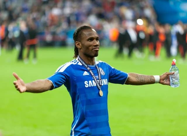 Didier Drogba, Chelsea football player, celebrating on the pitch with outstretched arms.