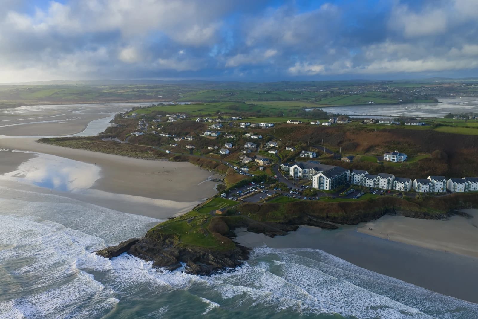 Aerial view of Inchydoney village and beach with houses and hotel.