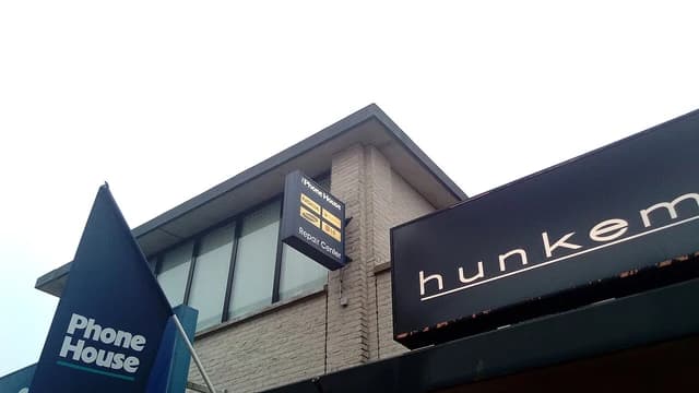 The Phone House Repair Center sign on a brick building with a flag nearby.