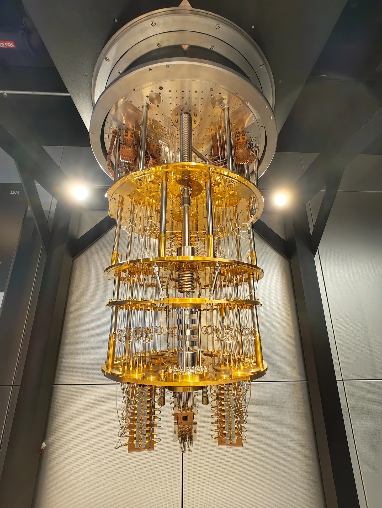 IBM Quantum System One, a golden-toned quantum computer, hanging within a chamber.