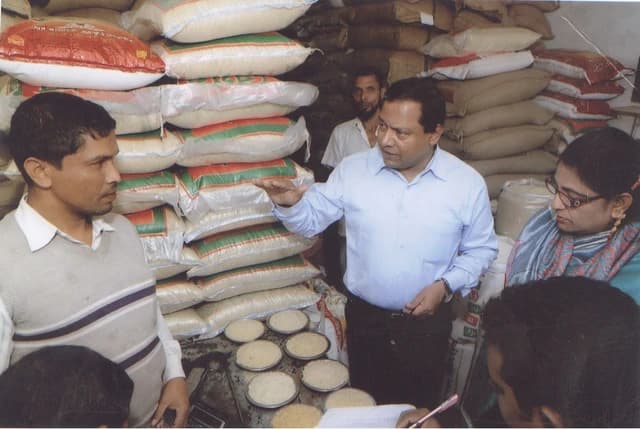 Minister of State for Textiles and Jute inspecting rice warehouses with other officials.