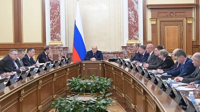 Mikhail Mishustin, Prime Minister of Russia, sits at a large conference table with officials.