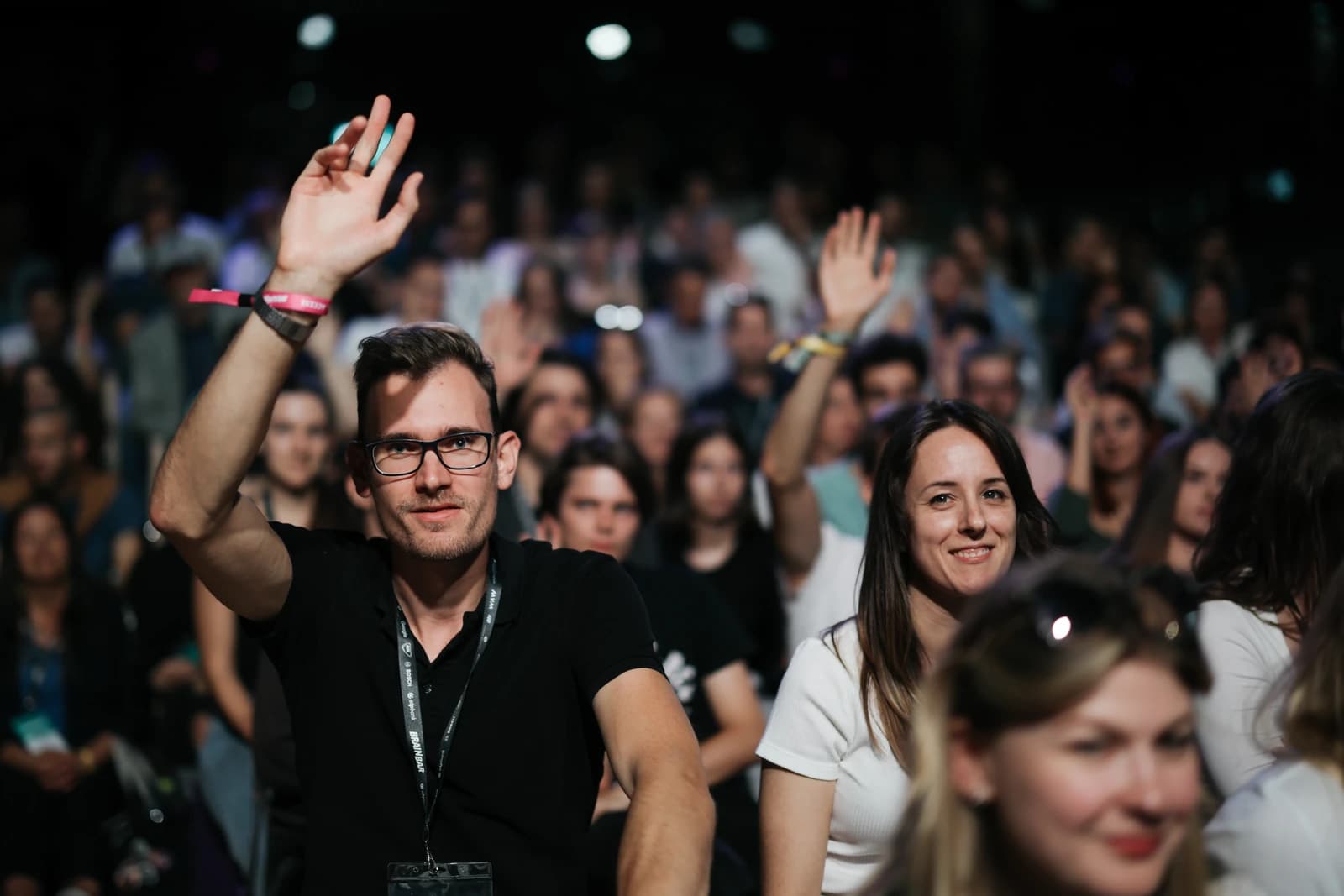 Audience members raising hands during a presentation at a conference.