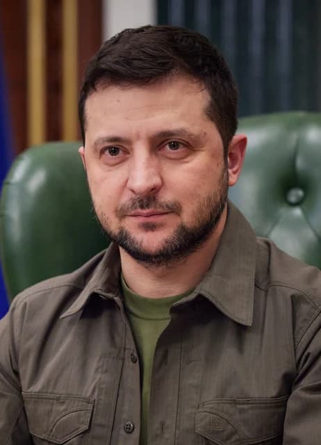 Volodymyr Zelenskyy, President of Ukraine, sits in a chair indoors.