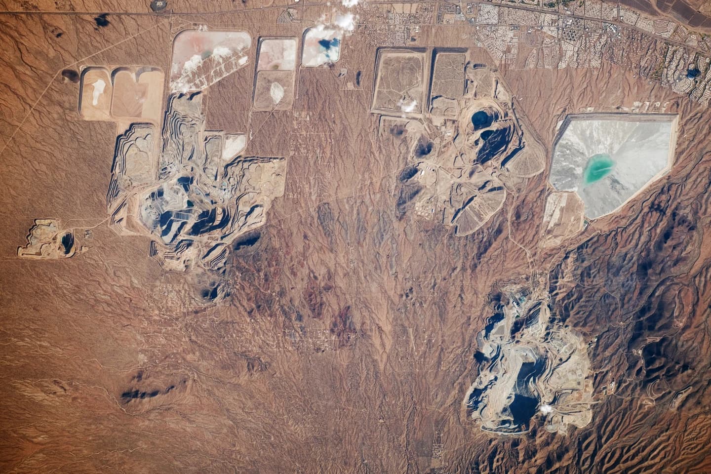 Aerial view of multiple open pit mines and vast surrounding landscape.
