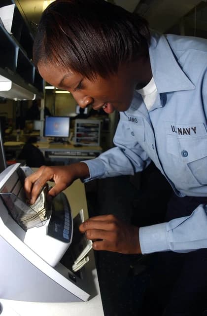 Disbursing Clerk 3rd Class Lakisha Williams verifying cash on a counting machine.