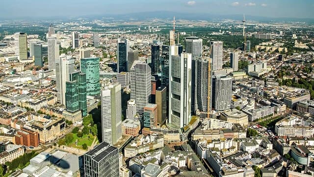 Aerial view of Frankfurt am Main, Germany with numerous skyscrapers under a blue sky.