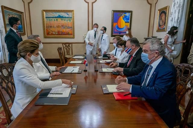 Secretary of State Mike Pompeo, wearing a US flag face mask, sits at a meeting table.