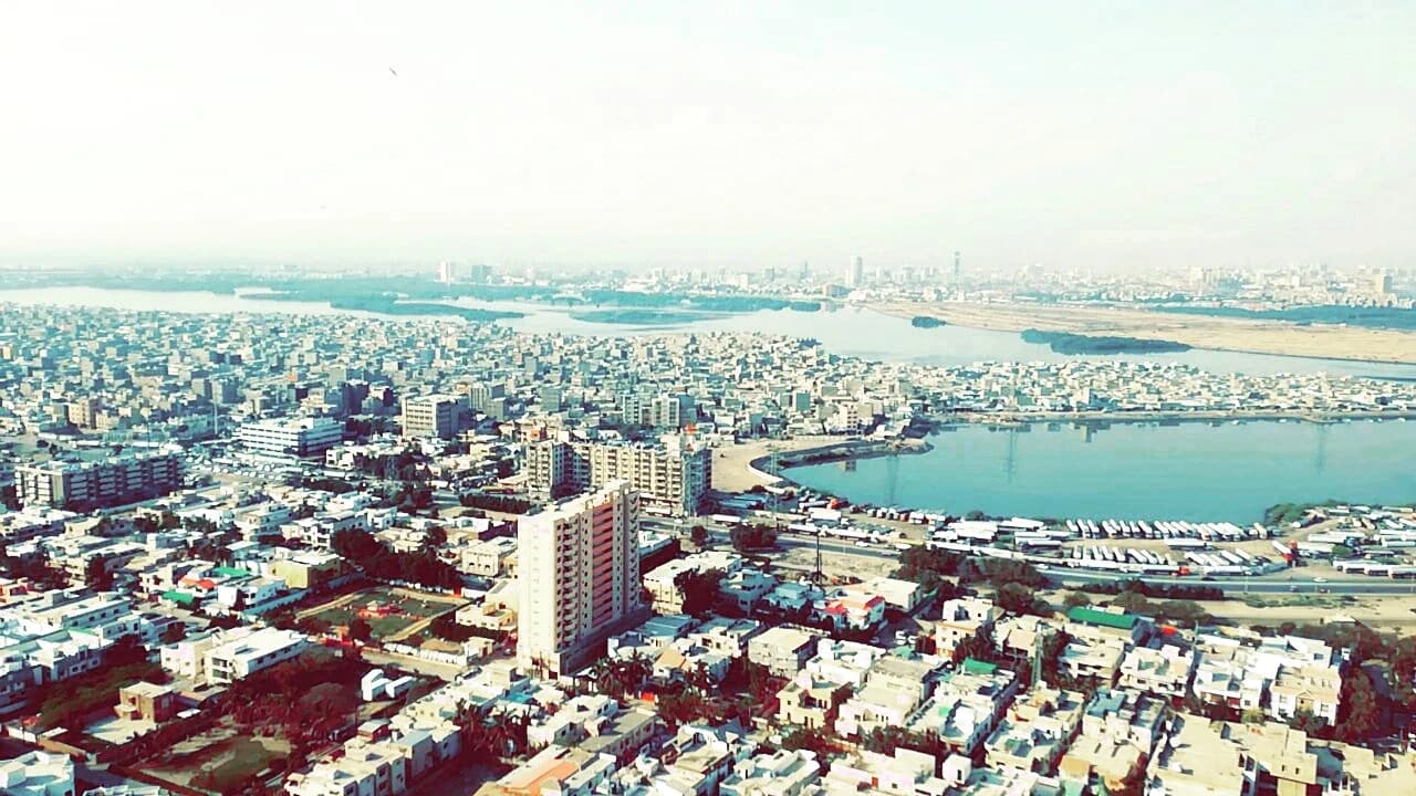 Aerial view of Karachi cityscape with buildings and rivers in the distance.