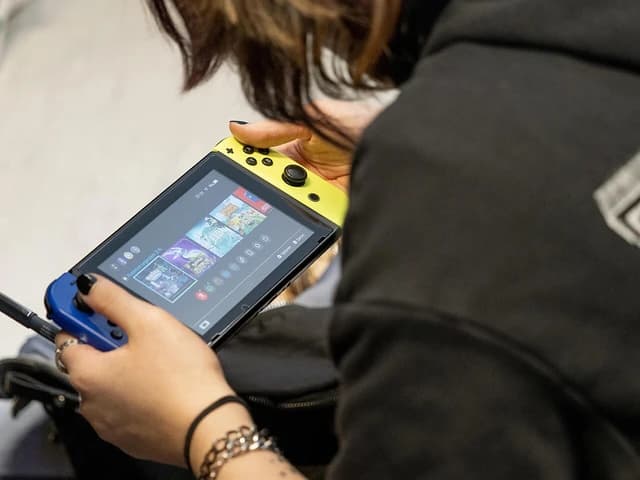 Person holding and playing a Nintendo Switch console.