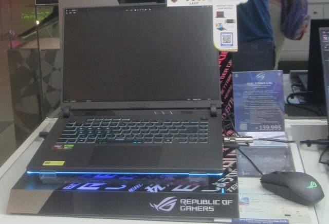 An ASUS ROG Strix G16 laptop with an empty screen, a mouse beside it.