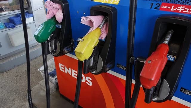 Close-up of multiple fuel nozzles, green, yellow, and red, at a gas station pump.