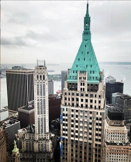 Aerial view showing 40 Wall Street building with green roof and other skyscrapers in New York City.