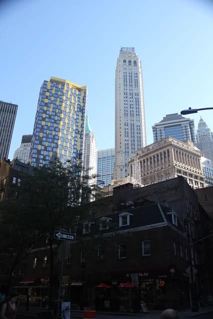 Skyscrapers and historic buildings in the Financial District, New York City, under a clear sky.