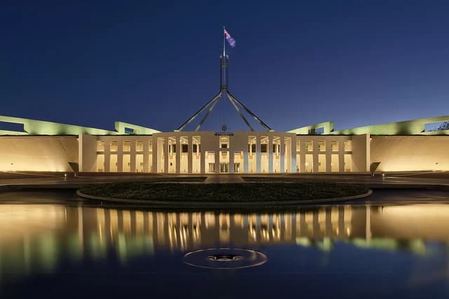 Parliament House in Canberra, Australia, illuminated at dusk with a flag flying.