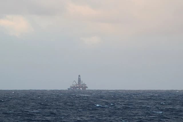 An offshore oil platform operating in the North Sea under a cloudy sky.