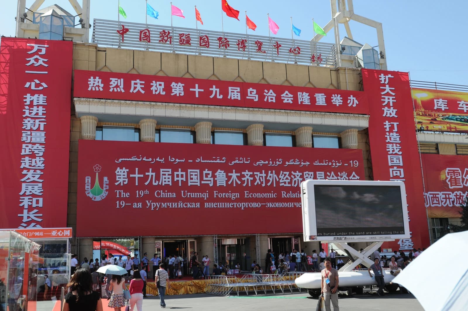 Exterior of building in Urumqi, China, with large red banners advertising a conference.