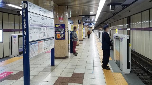 An empty Tokyo Metro Hanzomon Line station platform with a line guide and timetable.