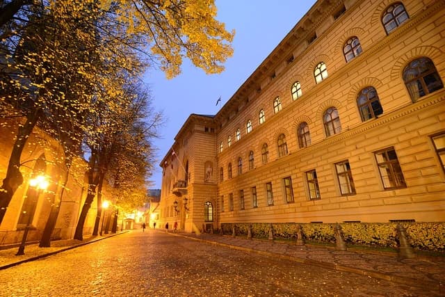 Exterior of the Saeima building in Latvia at dusk, with streetlights illuminating the foreground.
