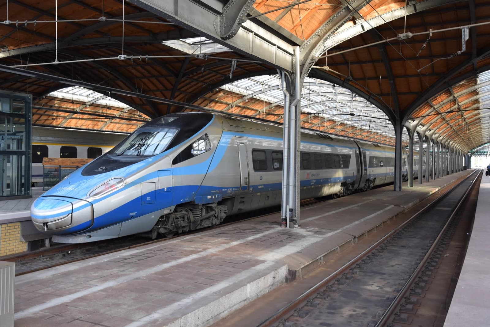 PKP Intercity Pendolino train parked at a station platform under a covered roof.