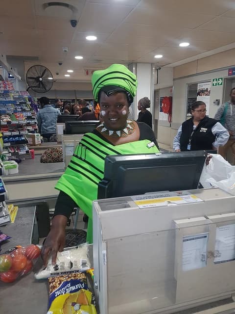 South African supermarket checkout woman scanning groceries at a register.