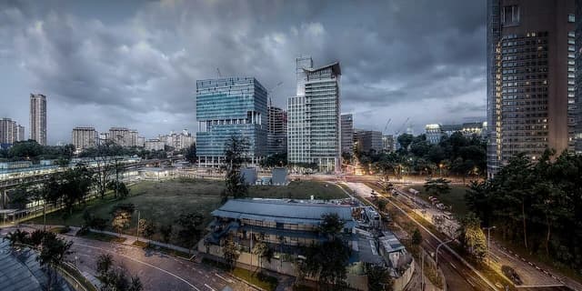 Singapore cityscape with modern buildings under a cloudy sky on a rainy evening.