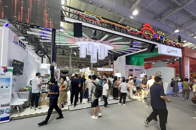People walking around and interacting at the Beijing Tourism Group booth at a trade fair.