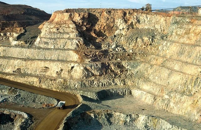 A large 120-ton ore truck on a road in an open-pit gold mine.