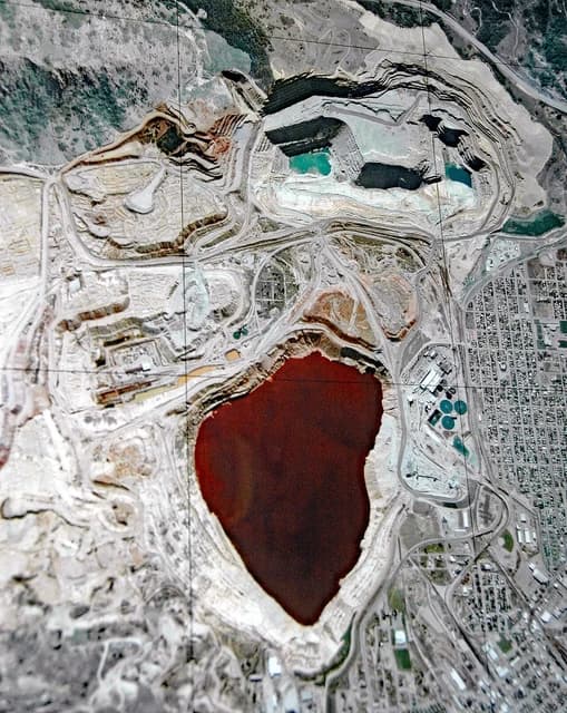 Aerial view shows the vast, reddish-brown Berkeley Pit and surrounding mining operations in Butte, Montana.