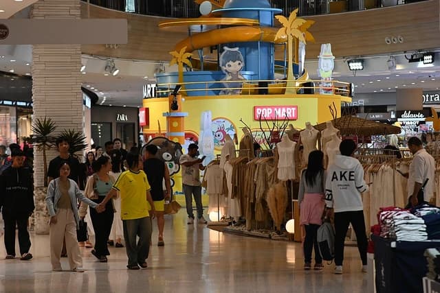 People walk through a shopping mall, some looking at merchandise in a pop-up store.