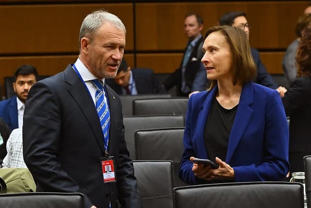 Man and woman, possibly IAEA officials, conversing during a meeting.