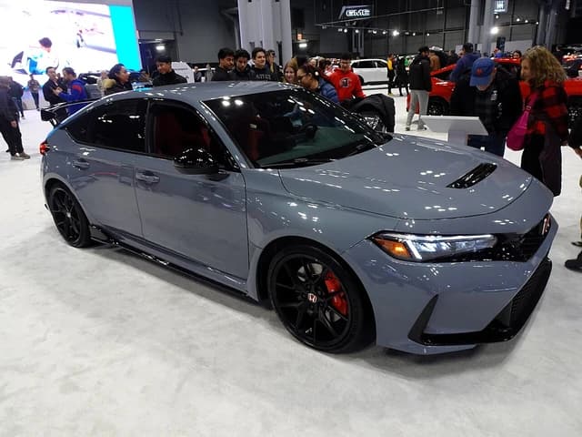 A gray 2024 Honda Civic Type R is on display at an auto show.