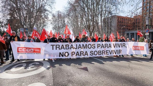 People marching in a street demonstration, carrying a large banner.