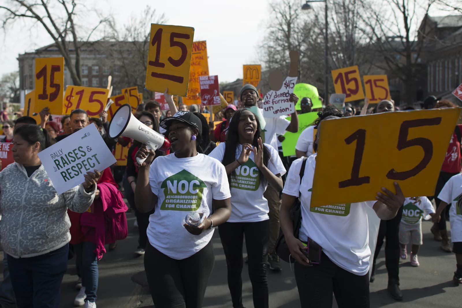 Protesters, including a woman with a megaphone, advocate for a $15 minimum wage during a march.