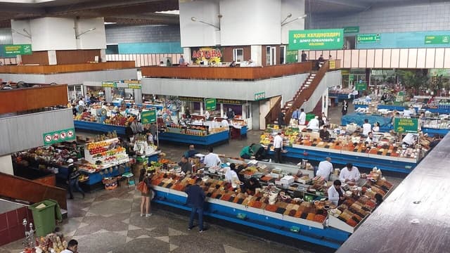 Overhead view of a bustling market with stalls displaying various goods and people walking.