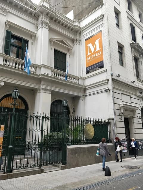 Exterior of Museo del Banco Central building with Argentine flags and a street sidewalk.
