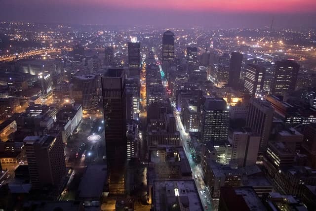 Aerial view of Johannesburg's inner city at dusk, with many illuminated buildings.