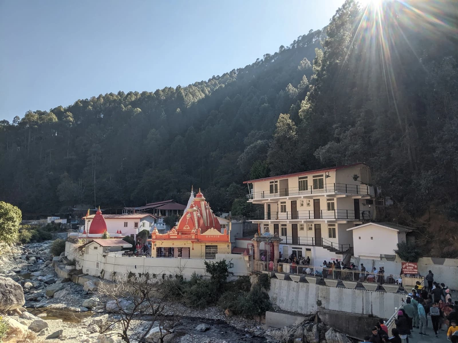 Kainchi Dham temple complex in Nainital with forested hills and a river.
