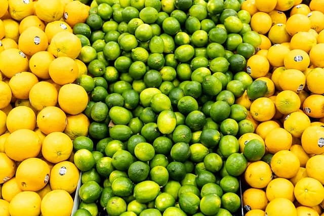 Green limes and yellow lemons are side-by-side in a grocery store produce section.