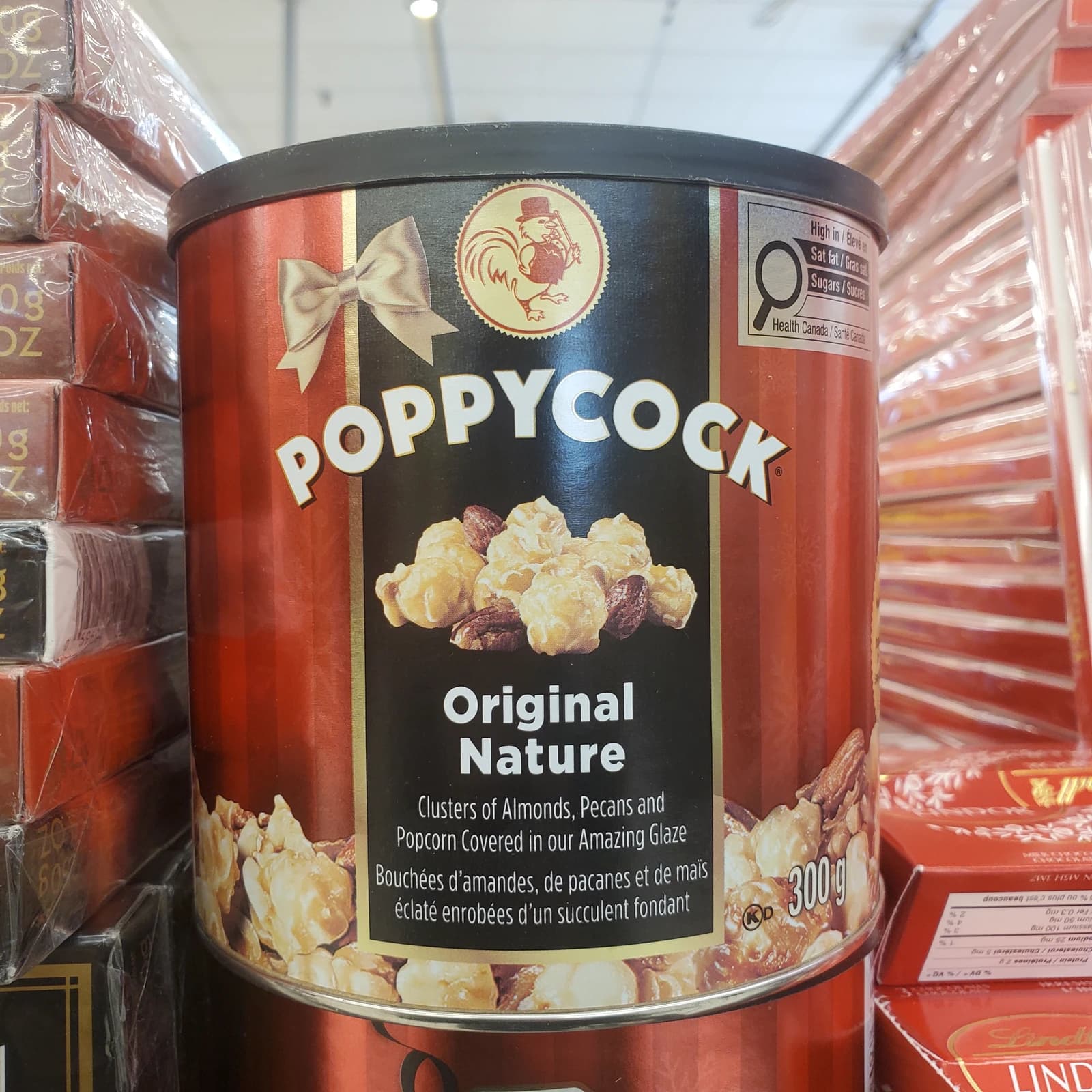 A red and black tin of Poppycock 'Original Nature' popcorn with Canadian health labels.