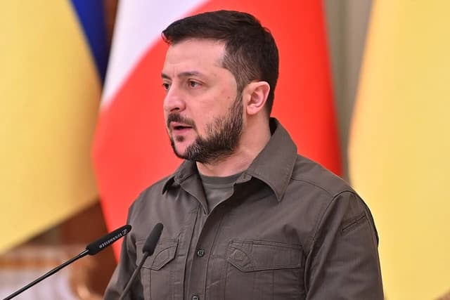 Volodymyr Zelenskyy, President of Ukraine, speaking at a podium with microphones.