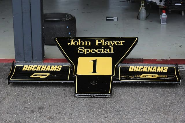 Sign for 'John Player Special' with a number '1' and 'Duckhams' logos in a garage.