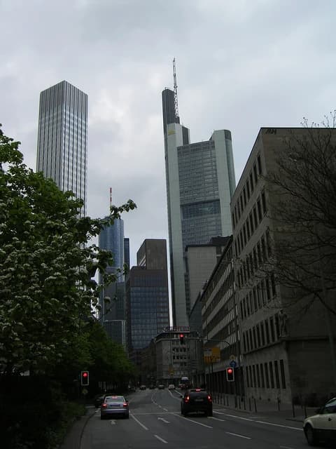 Skyscrapers of Frankfurt's financial district, including the Commerzbank Tower, under a cloudy sky.