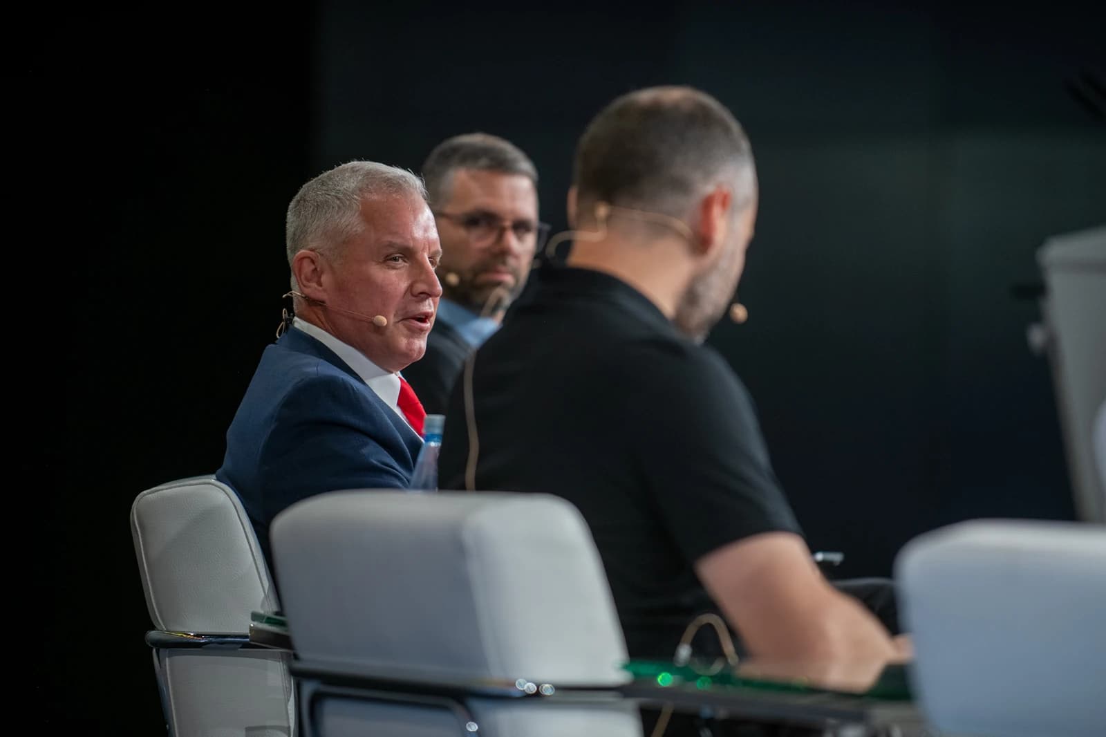 Man with gray hair and red tie speaking at a panel discussion.