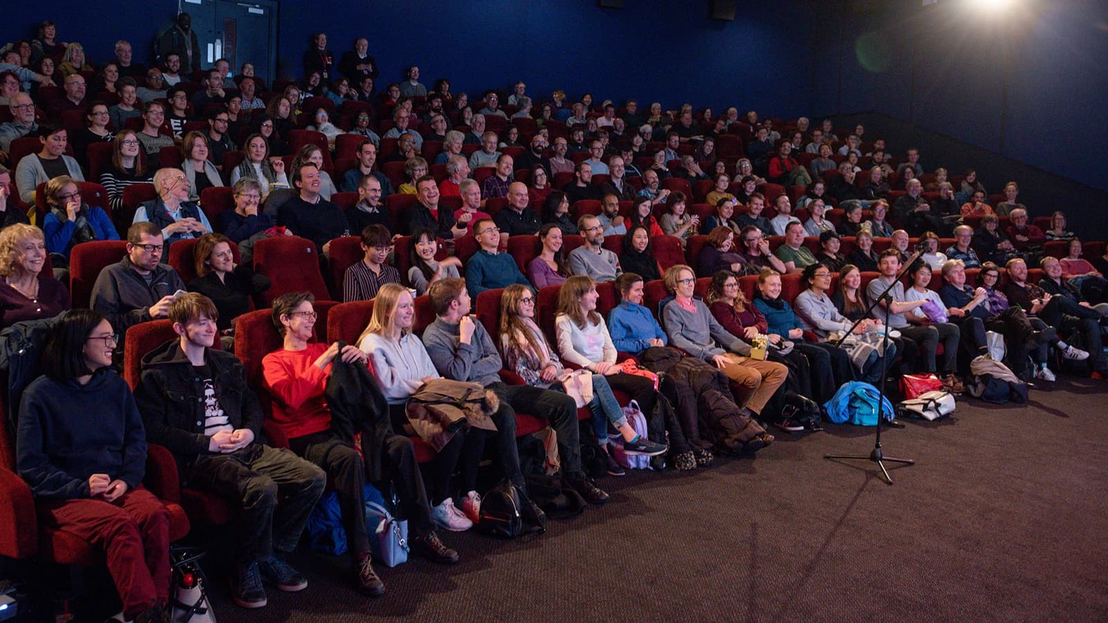 Audience members seated in a cinema auditorium watching a film screen.