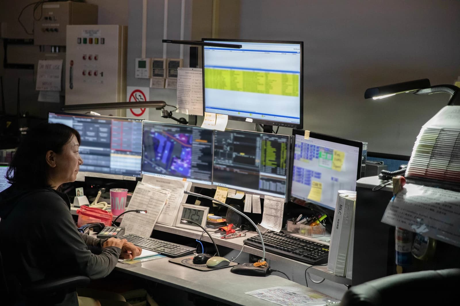 Public safety dispatcher at a console with multiple computer monitors displaying data.